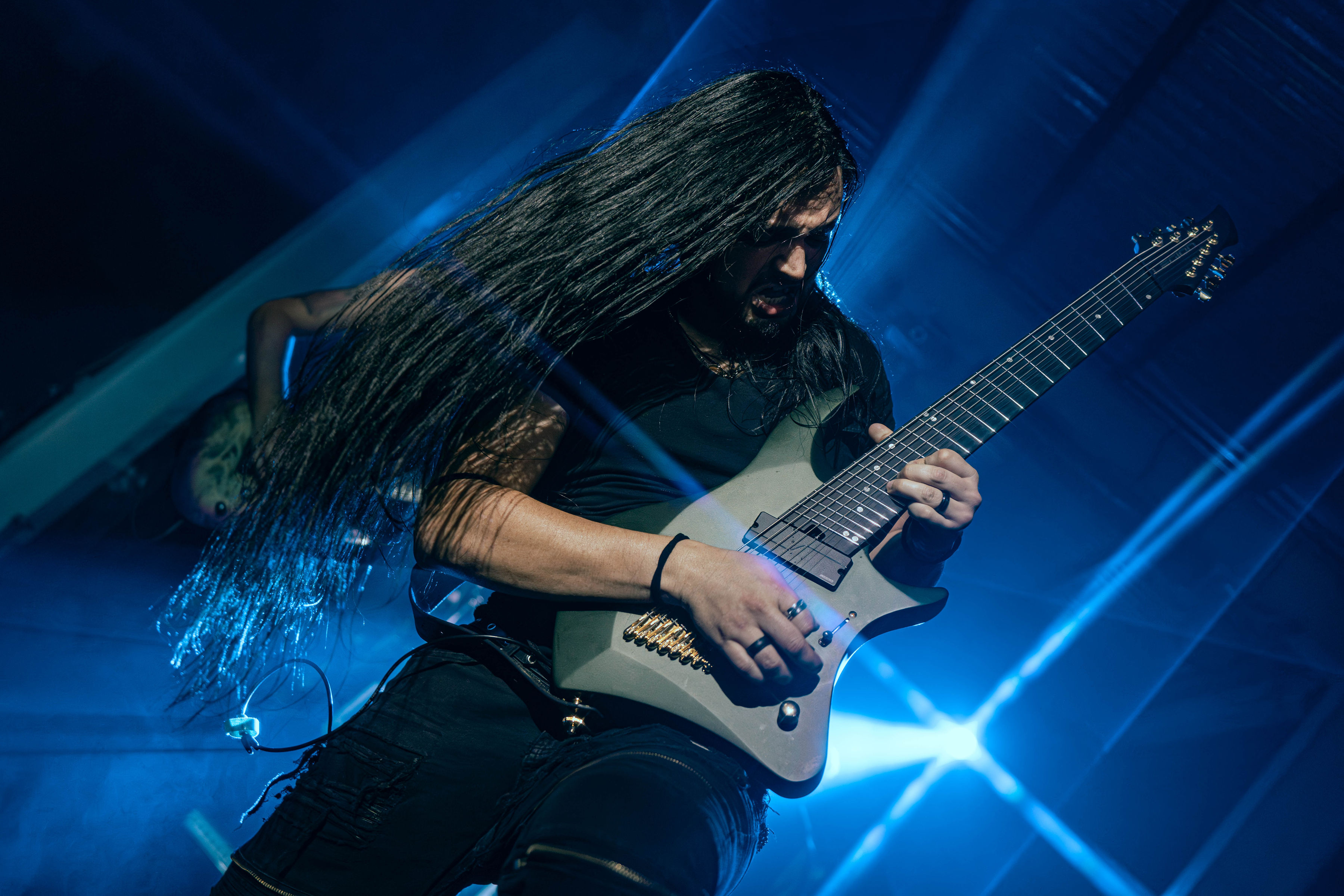 Andrés Castro playing guitar on a blue-lit stage